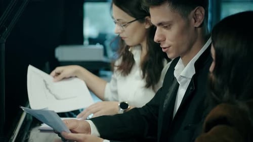 Office Workers Reviewing Documents and Charts at Desk