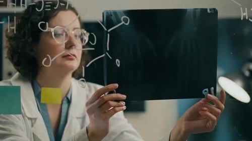 Glass board, Woman chemist analyzes x-ray picture on bright light In scientific laboratory