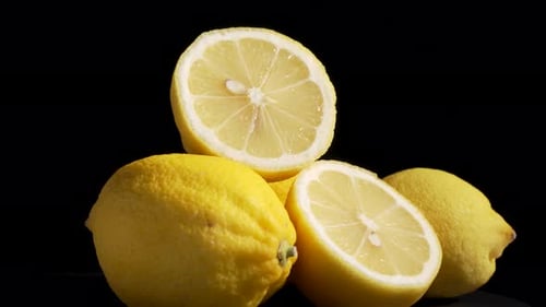 Fresh Yellow Lemons with Juicy Slices on Black
