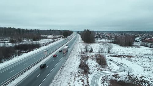 Atemberaubende Luftaufnahme einer schneebedeckten Autobahn und ihrer Umgebung in einer wunderschönen Winterlandschaft