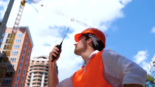 Construction Worker Communicating with Walkie Talkie at Site