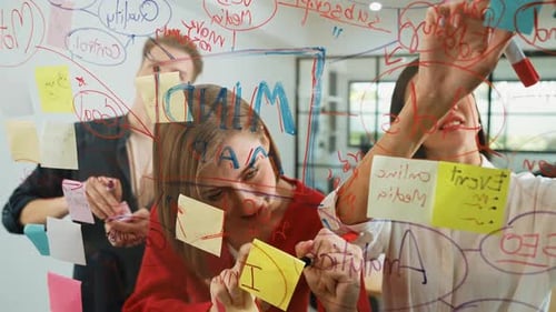 Team Collaborating on Glass Whiteboard in Office