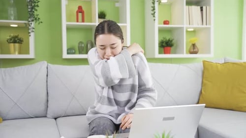Young Woman Coughing into Elbow Indoors