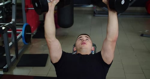 Man Lifts Dumbbells in Gym Setting