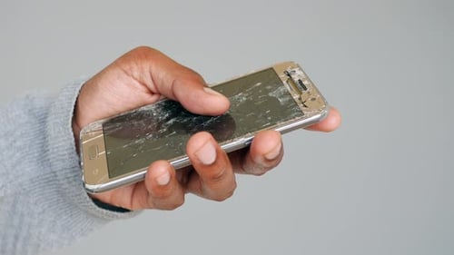 Hand Holds a Smartphone with a Shattered Screen