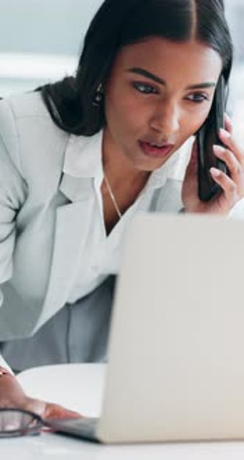 Happy Woman Works on Laptop While Talking on Phone
