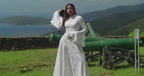 A young lady dressed in a vintage-style wedding dress explores the ruins of a fort.
