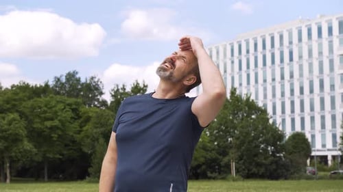 Man Stretches Neck Outdoors on Sunny Day