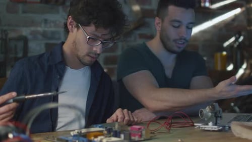 Zwei Studenten studieren Elektronik und Löten in einer Garage.