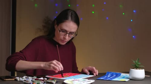 Woman Painting with Watercolors at a Table Indoors