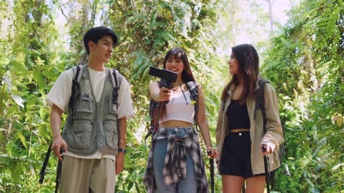 Grupo de vloggers de mochileiros asiáticos se divertem viajando juntos pela floresta.