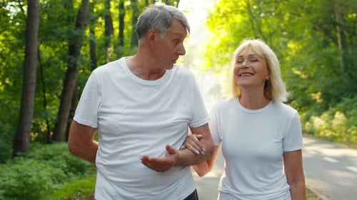Active Senior Couple Enjoying a Walk Together in a Sunlit Park Setting
