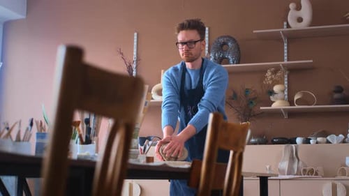 A Young Potter Guy Creates a Sculpture in a Bright Workshop with His Hands The Male is in a Creative