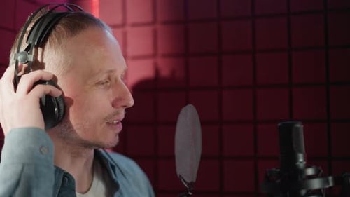 Man Adjusting Headphones in Recording Studio with Acoustic Panel Background