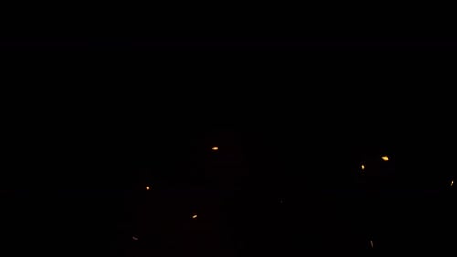 Glowing Embers Floating Against Black Background