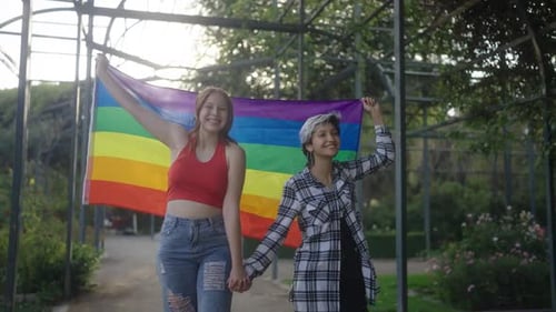 Couple Holding Hands with Pride Flag in Park