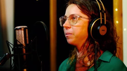 Voice-over actress recording in the studio with a professional sound microphone.