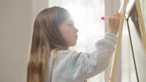 Girl Drawing on Easel Indoors During the Day