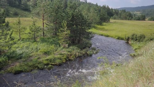 An amazing beautiful landscape view of a zigzag river streaming in the green fields.