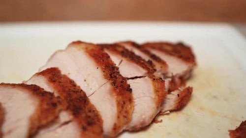 Sliced, grilled, boneless, skinless chicken breast on the cutting board - slow pull back macro view