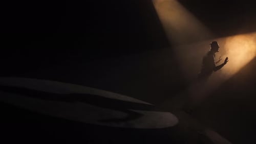 Silueta masculina de pie en un Dramático cruce de luces en el escenario