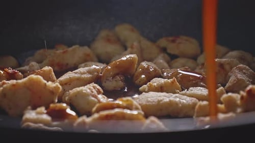Cooking sizzling diced chicken with savory sauce indoors