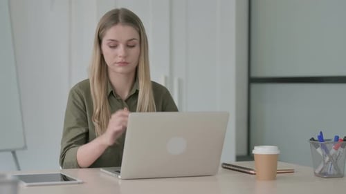 Woman Working at Laptop Rubbing Wrist at Desk
