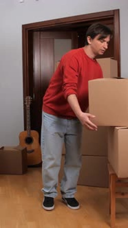 Man Stacking Cardboard Boxes in Home