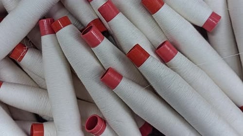 Close Up of White Yarn Spools with Red Tips