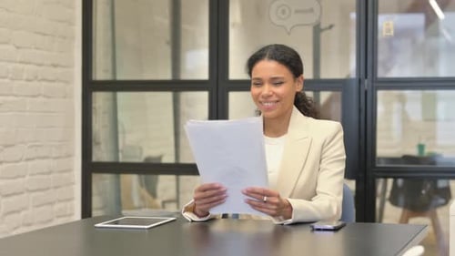 Businesswoman Reads Documents and Smiles in Modern Office
