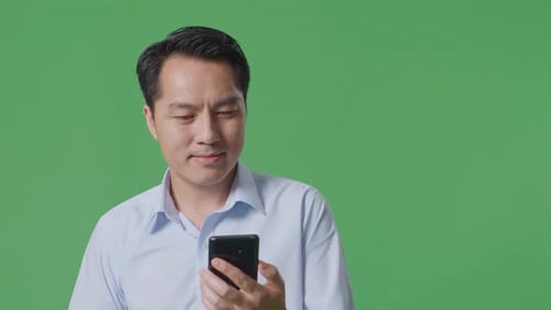Close Up Of Asian Business Man Using Mobile Phone While Walking On Green Screen Background