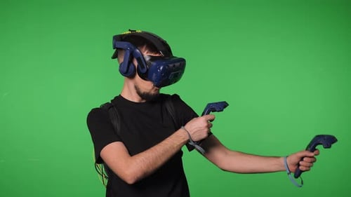 A Man Uses Virtual Reality Glasses to Play in a Studio on a Green Background