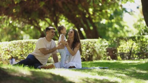 Happy Family Sitting on the Blanket in the Park