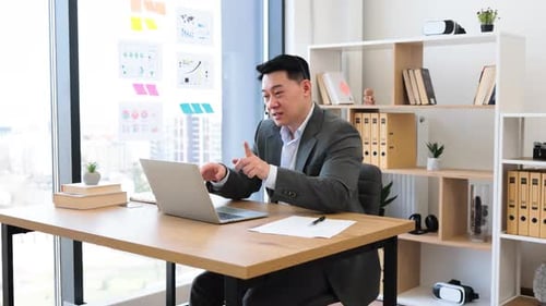 Asian Businessman Smiling During Online Video Call in Modern Office