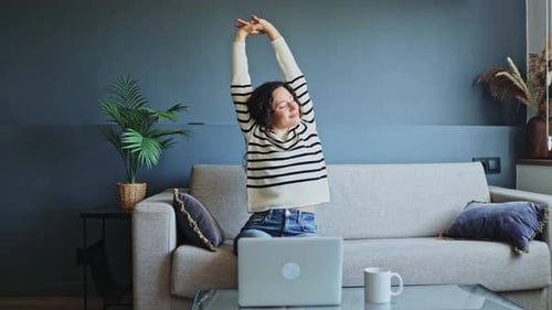Freelancer woman stretching while working from home