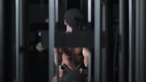 Athletic Man in the Gym Lifting Blocks on Rowing Machine Training on Block Device and Gym Equipment