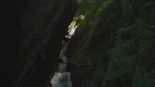 River Flows Through Narrow Gorge and Falls As Waterfall