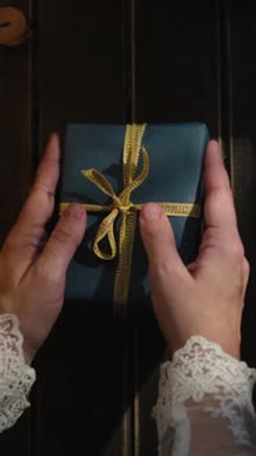 Hands Carefully Placing Wrapped Birthday Gift on Table