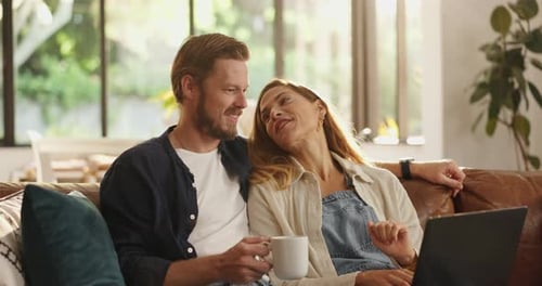 Happy Couple Laughing Together at Home With Laptop