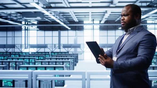 Trabalhador usa dispositivo digital no data center, garantindo que as plataformas estejam funcionando