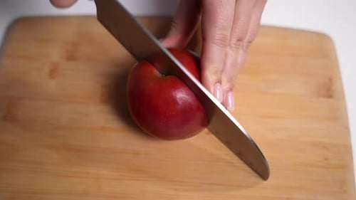Hands Cutting a Red Apple with a Knife