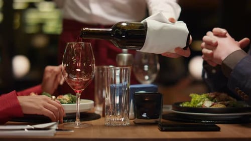 Waiter Pouring Wine Glass at Stylish Loft Restaurant Table. Unknown Couple Enjoying
