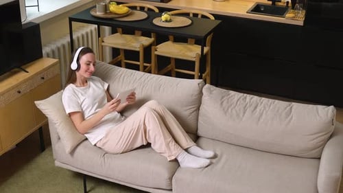 Young Woman Relaxing on Couch with Tablet