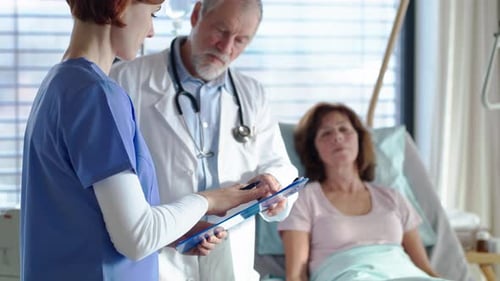Senior doctor talking to nurse in hospital ward portrait showing compassionate care