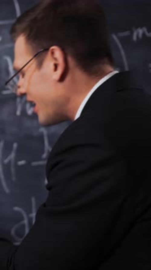 Vertical of Two Scientists Writing Discussing Math Equations and Formulas on a Chalk Desk Board