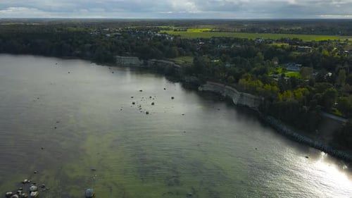 Aerial view of a limestone cliff bank at a seaside ocean shoreline during summer day, horizon seen.