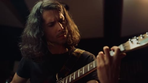 Excited guitarist playing electric guitar and enjoying rock music in recording studio