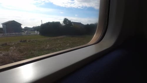 eine Aufnahme aus dem Inneren eines fahrenden Zuges, der durch ein Fenster nach draußen schaut