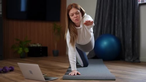 Engaging in a Home Workout Session with a Yoga Mat and Laptop for Fitness and Health