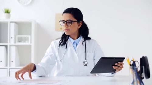 Woman Doctor Working at Desk with Tablet